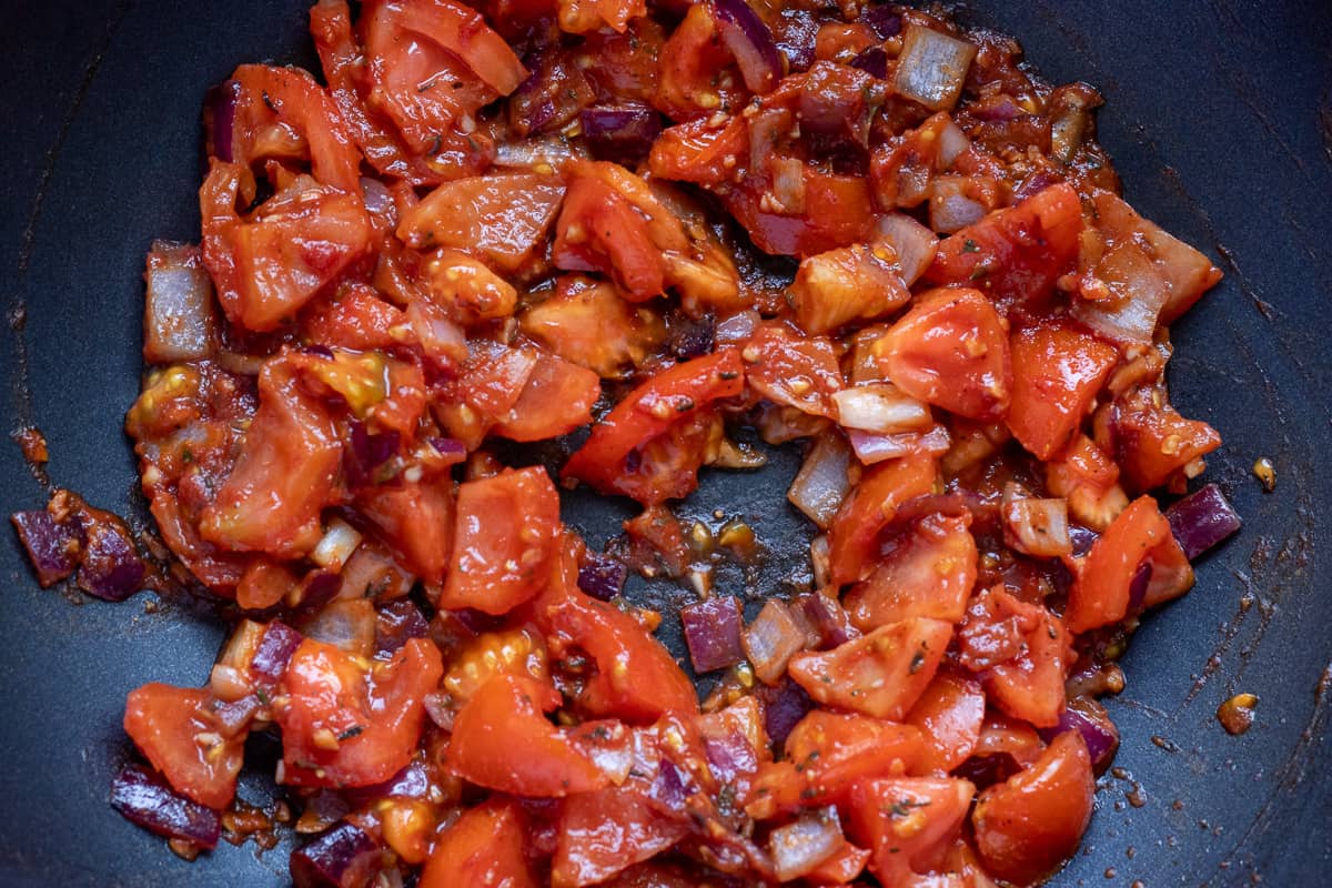 The tomatoes and tomato paste are added to the sautéed onions