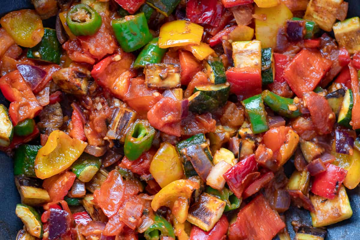 The vegetables are cooking in tomato sauce until soft