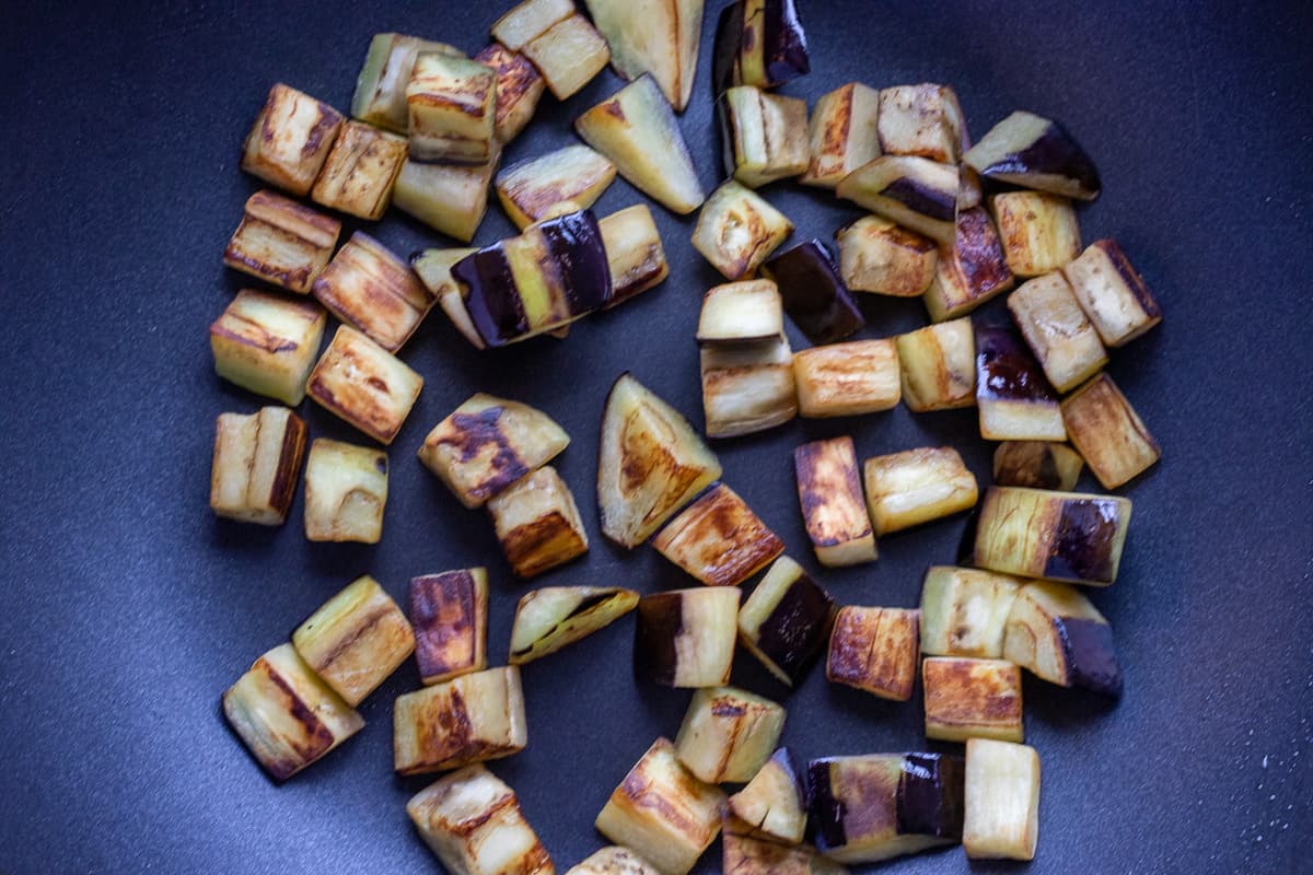 Sautéing the aubergines with olive oil in a wok