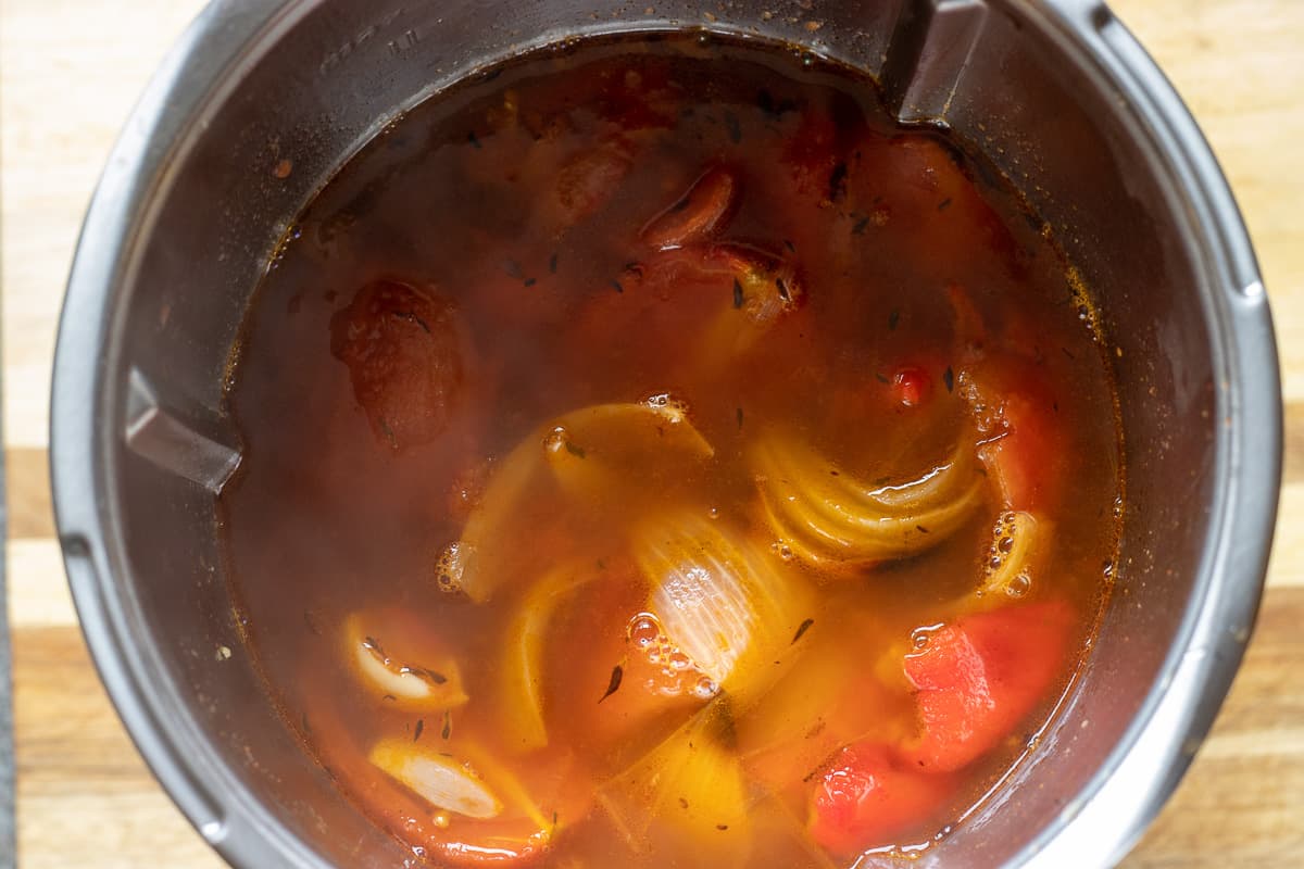 tomato and red pepper soup is in a bowl of a mixer