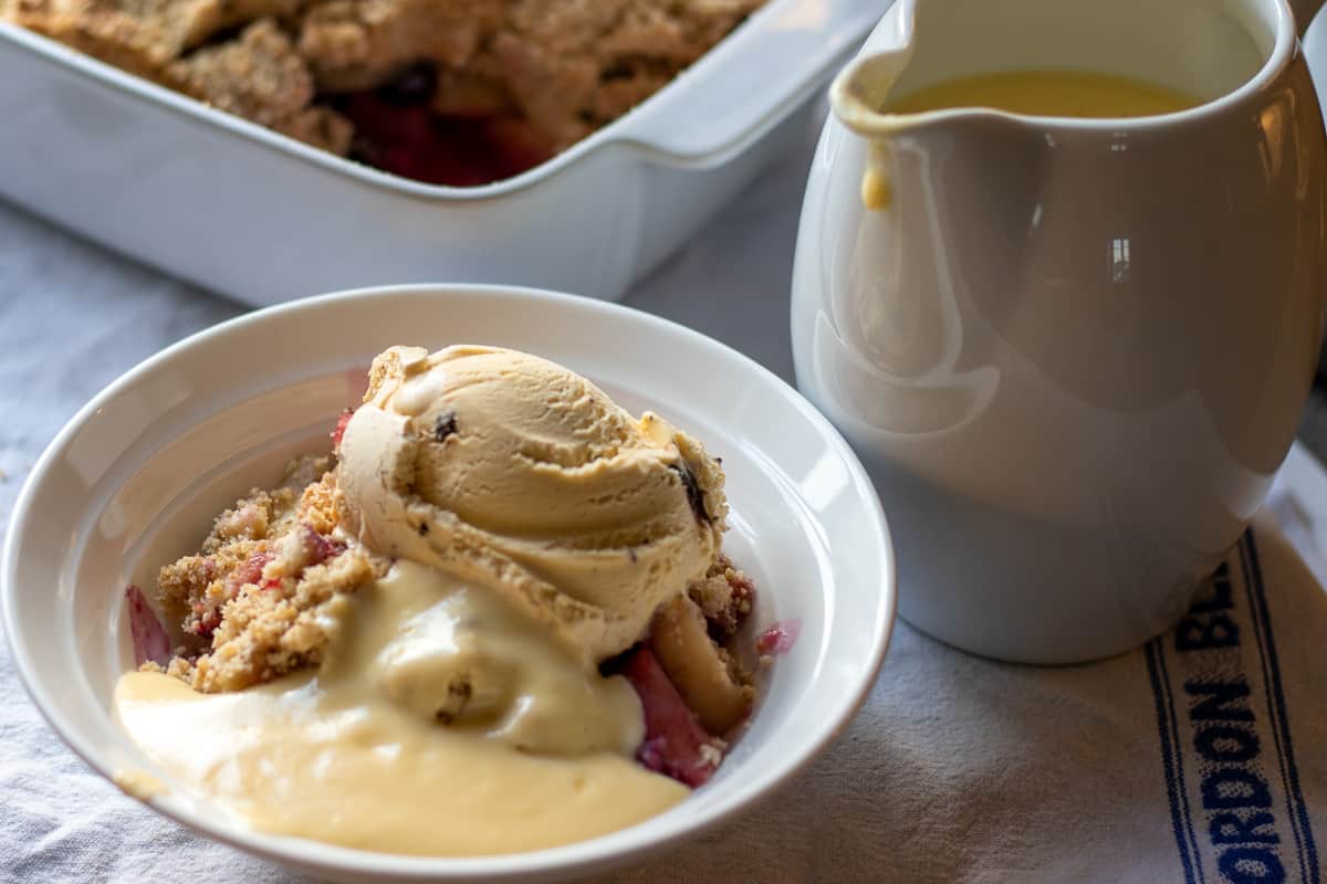 apple and blueberry crumble served in a bowl with custard