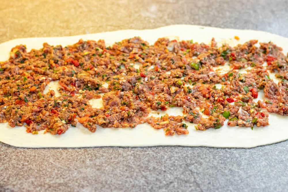 The dough is topped with ground meat.