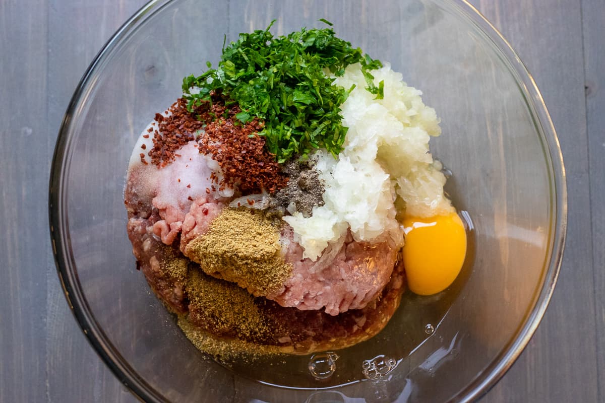 ground beef, egg, parsley, onion and spices are placed in a bowl for making kofta mixture