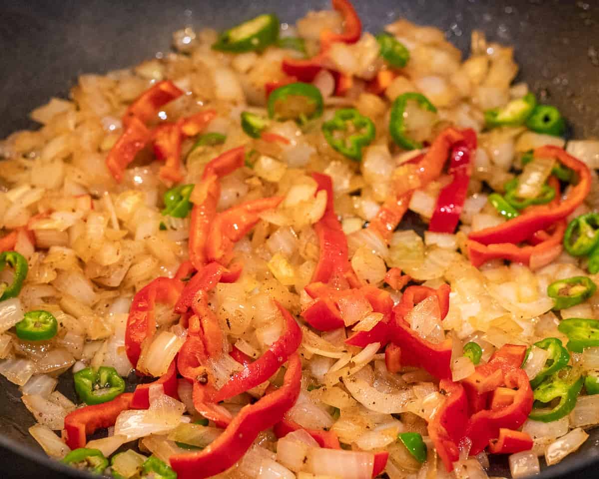 sautéing the sliced peppers and onions in a pan