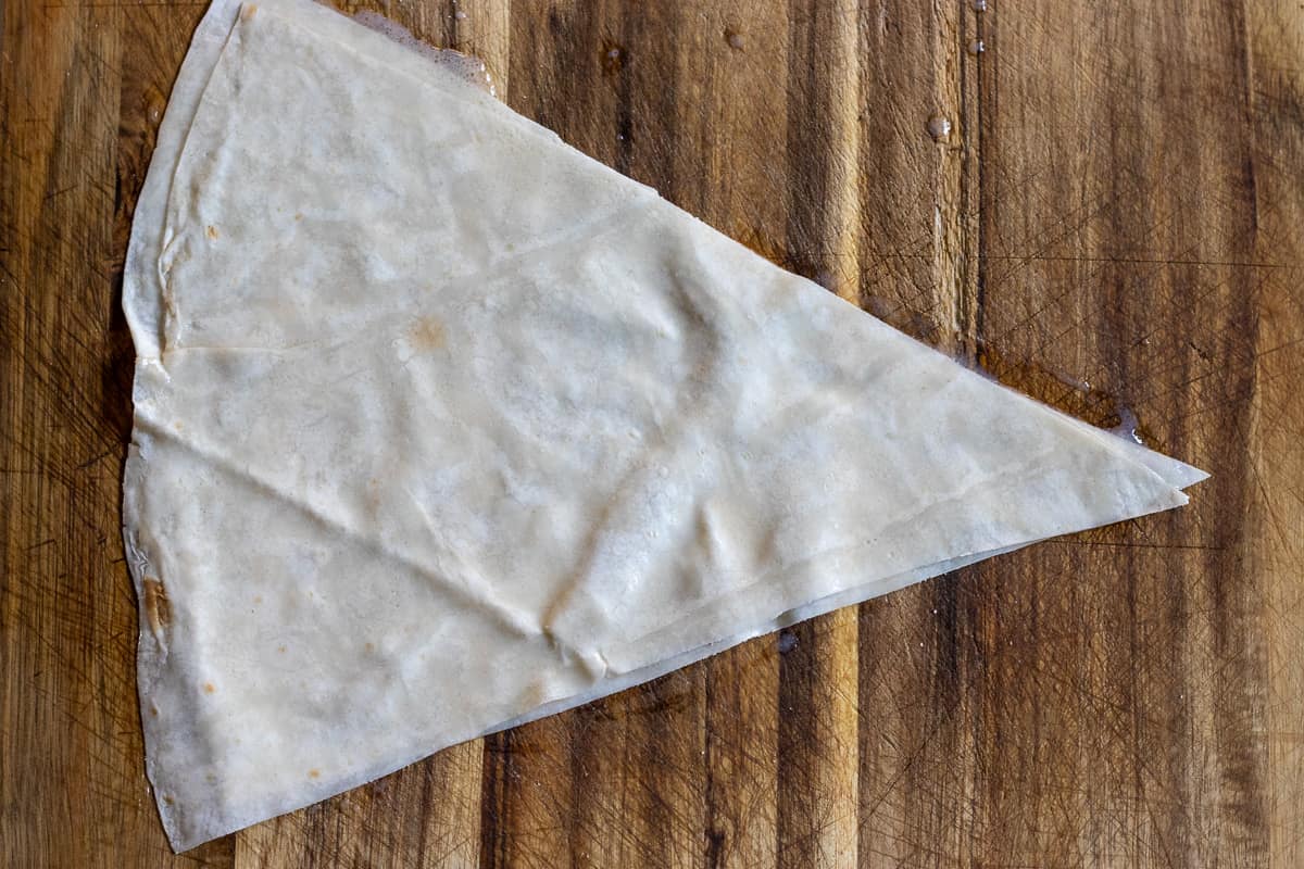 2 pieces of yufka triangles are brushed with sauce