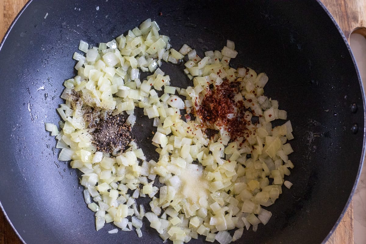 salt, pepper and chili are added to the sautéed onions