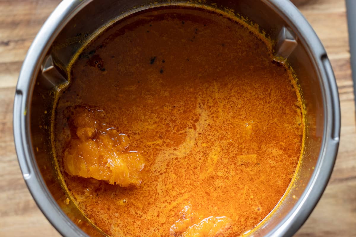 roasted butternut squash and soup base are in a bowl of the blender