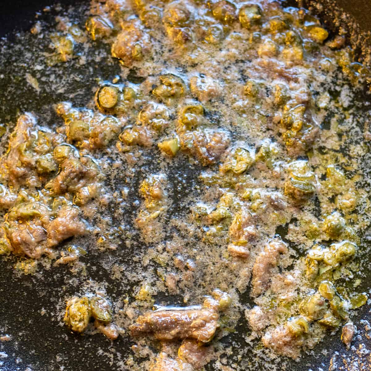 Chopped capers are added to the wok when anchovies are melted