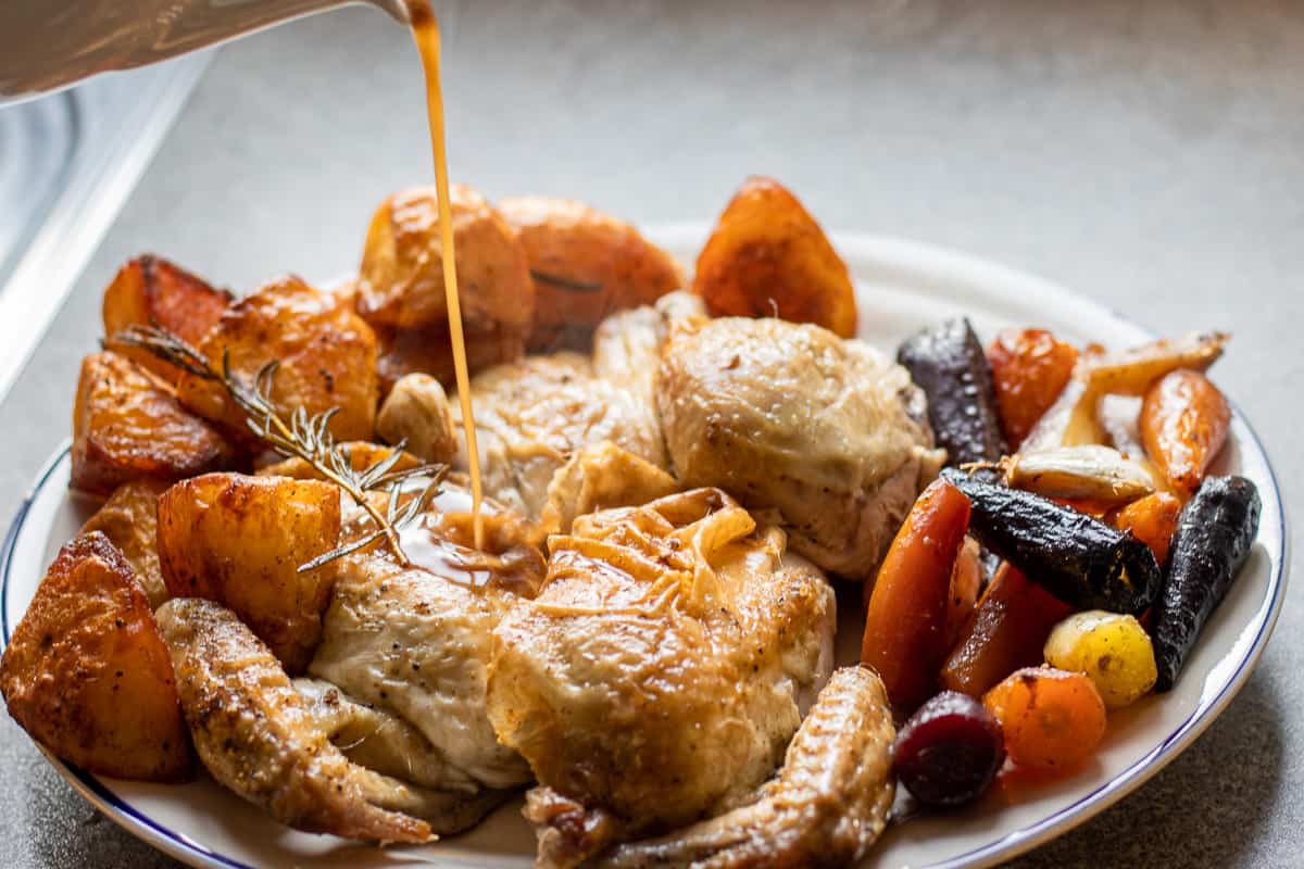 dutch oven roast chicken is served with vegetables and gravy