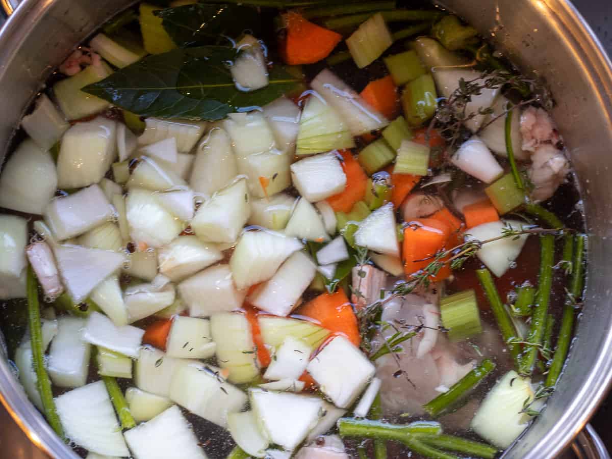 chicken bones are placed in a pot along with the mirepoix