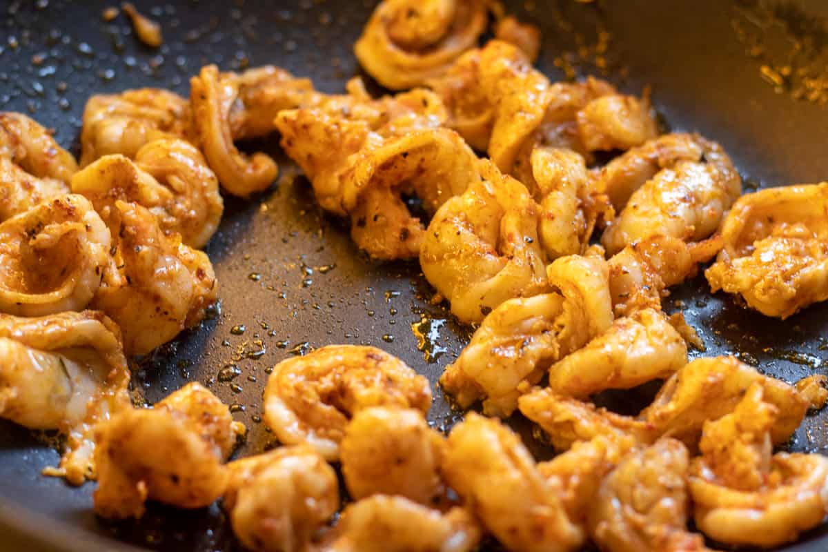 Sautéing the prawns in a pan with butter.