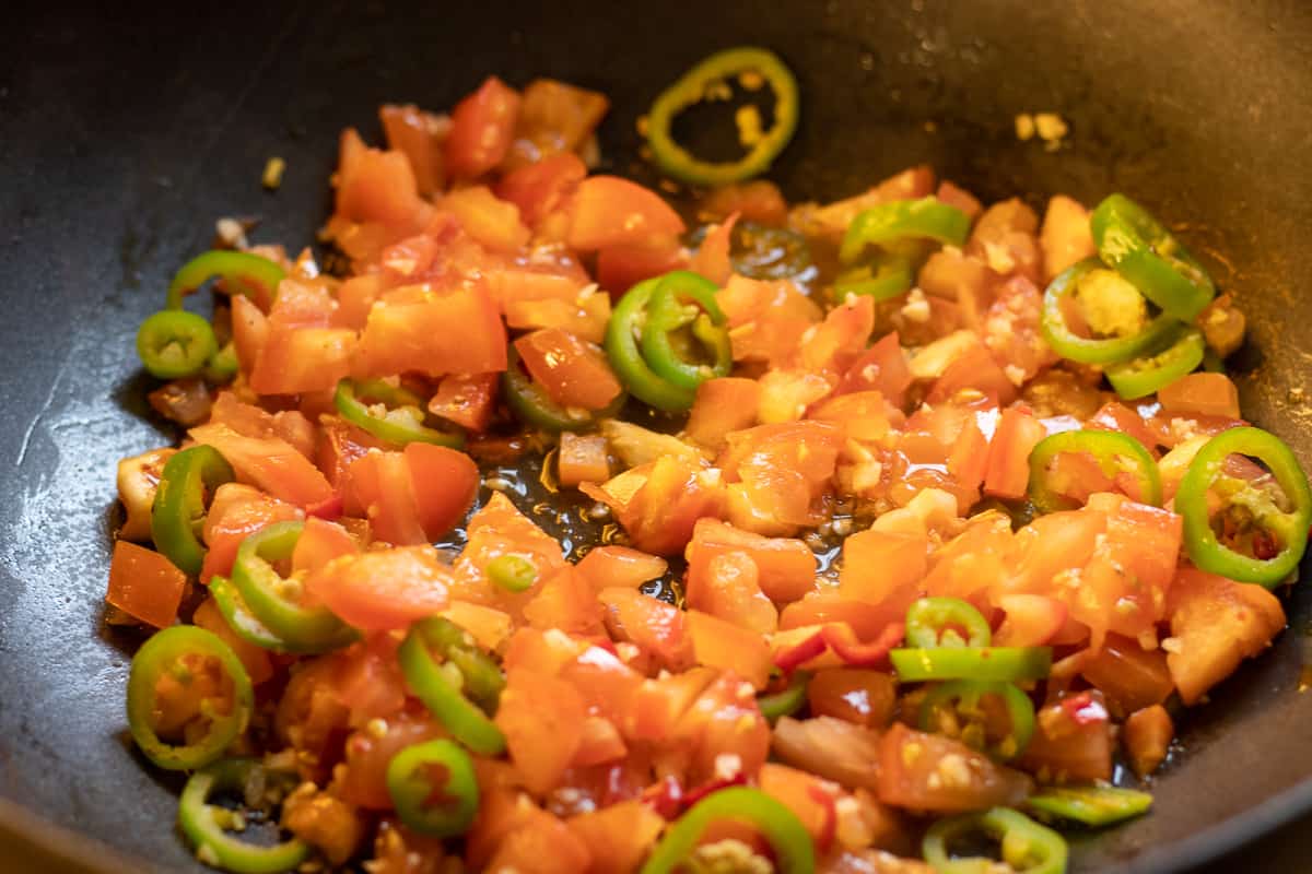 chopped tomatoes added to the pan with sautéed peppers