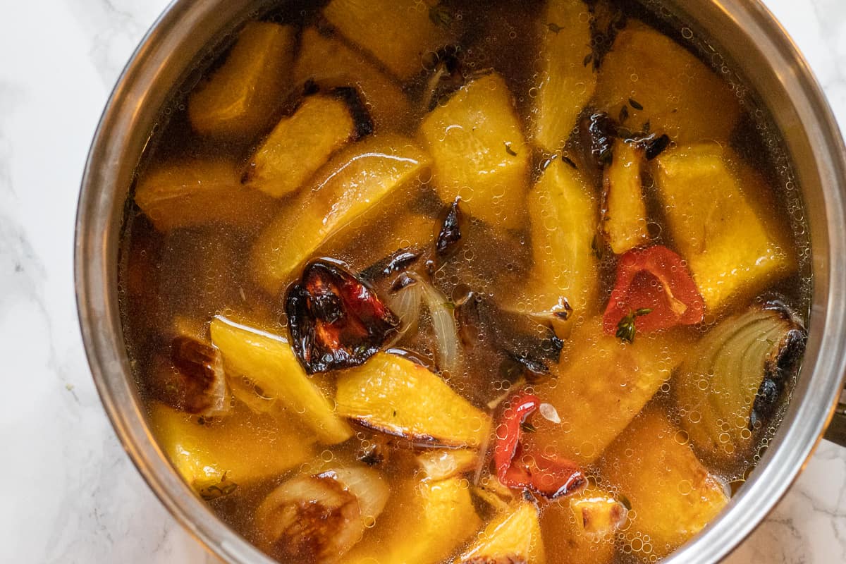 roasted veggies and stock are placed in a pot