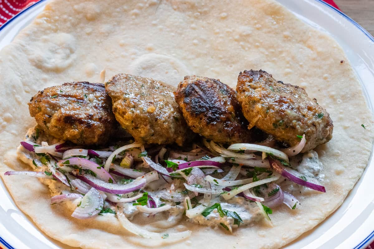 lamb koftas served on pita bread with yogurt dressing and onion salad