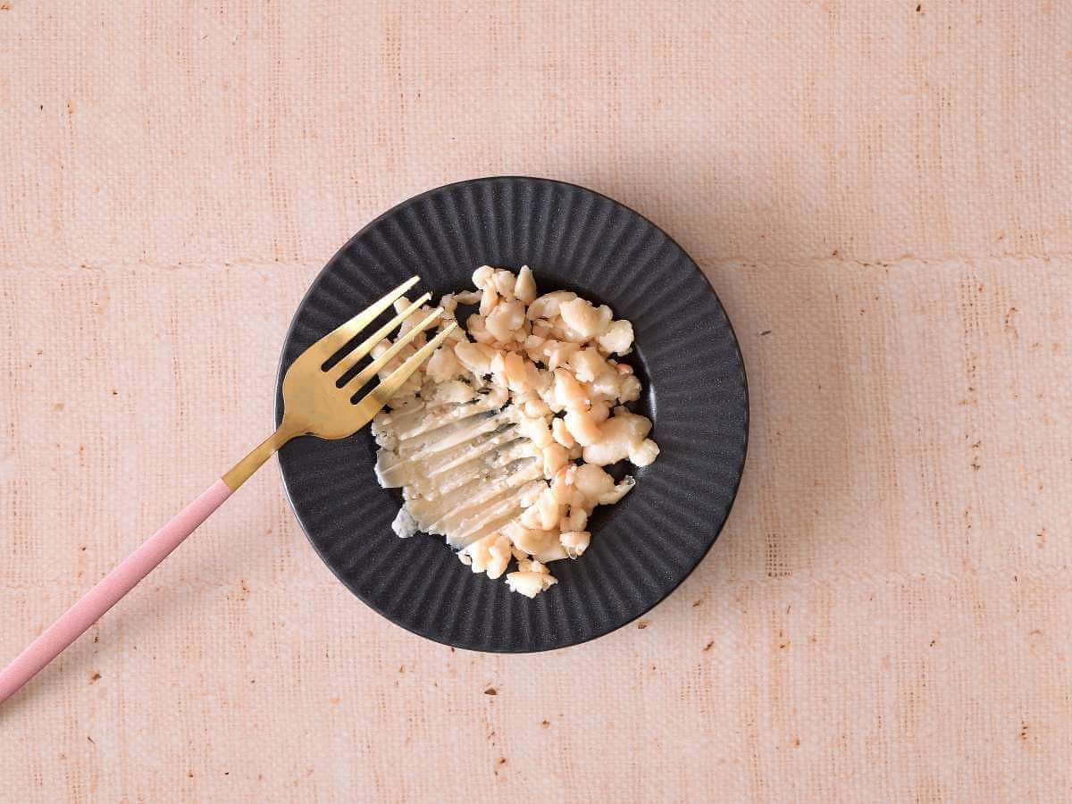 Mashing white beans using a fork.