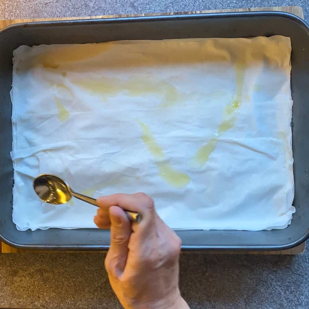 a layer of filo sheet placed on a tray and drizzled with butter