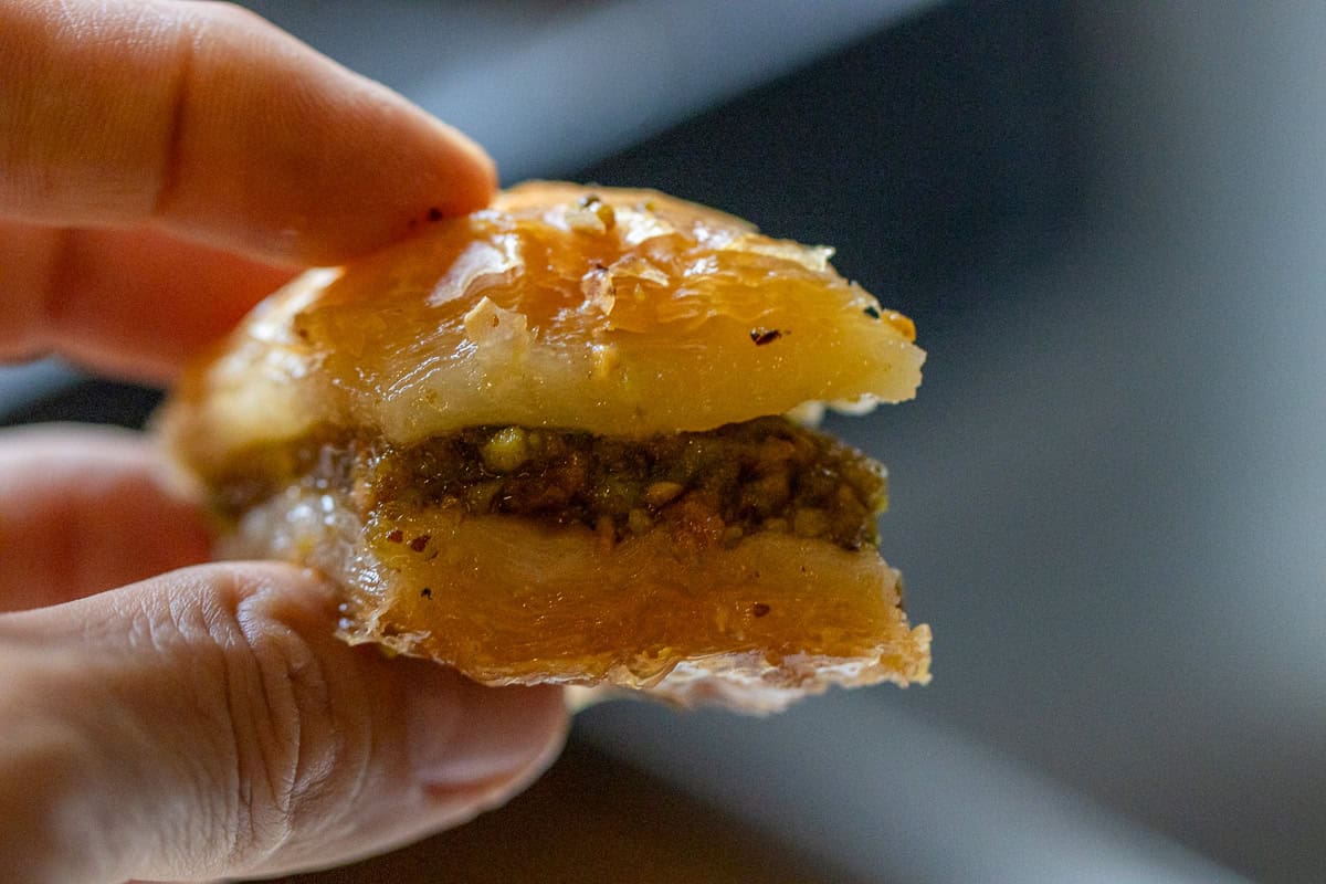 holding a piece of pistachio baklava