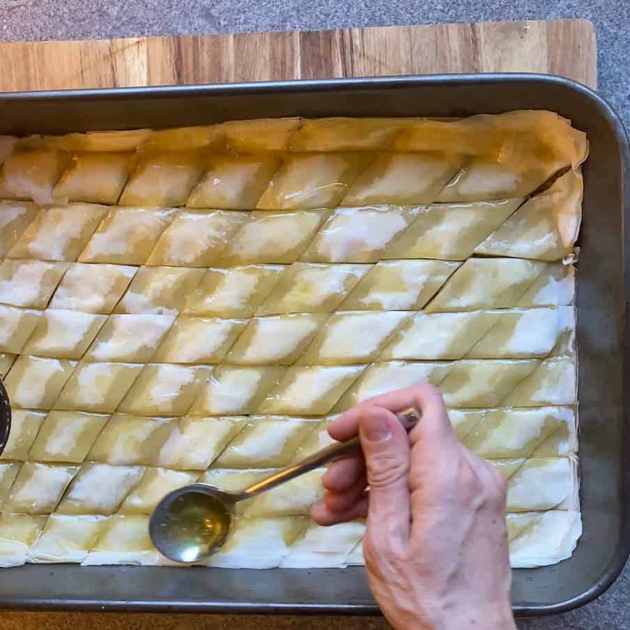 scattering the rest of the melted butter over the baklava