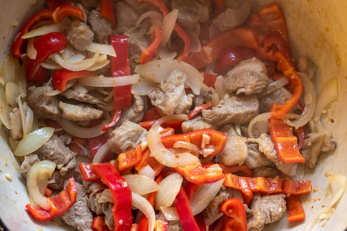 Sautéing the peppers with onions and lamb
