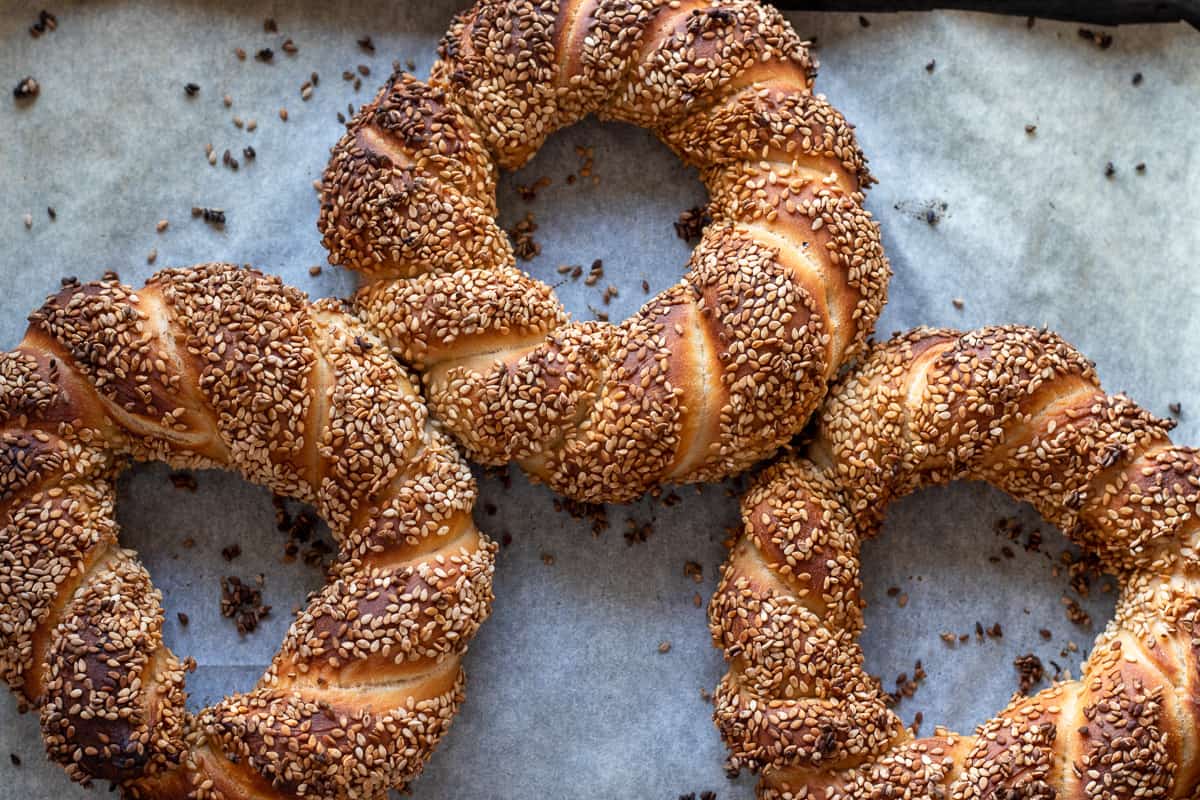 3 pieces of freshly baked simit are on a tray lined with paper