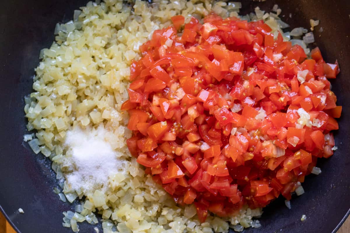Chopped tomatoes and salt are added to sautéed onions