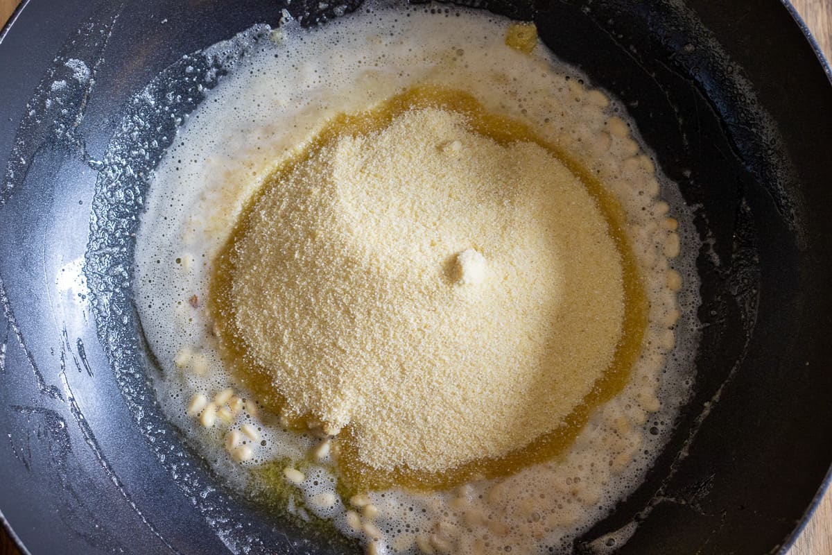 The semolina is added to the pan with pine nuts