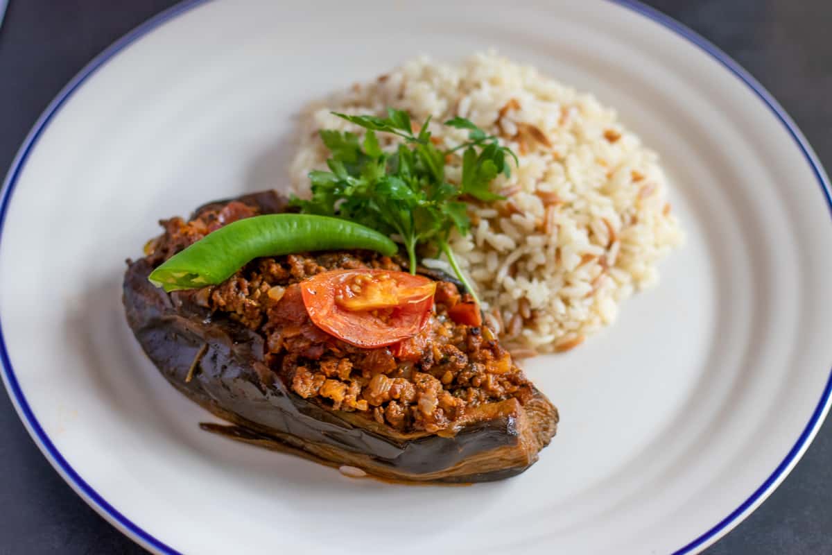 Karniyarik - mince stuffed aubergine is served on a plate with Turkish pilaf