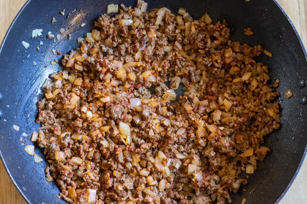 the tomato paste and chopped tomatoes are added to the pan