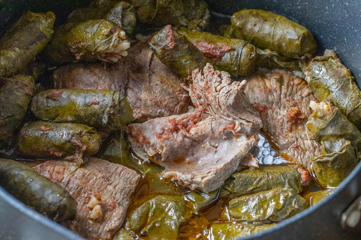 meat stuffed wine leaves are cooked in a pan with lamb meat