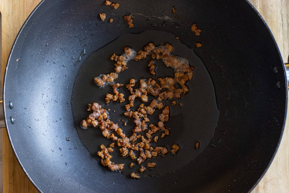 rendering the lamb fat in a wok