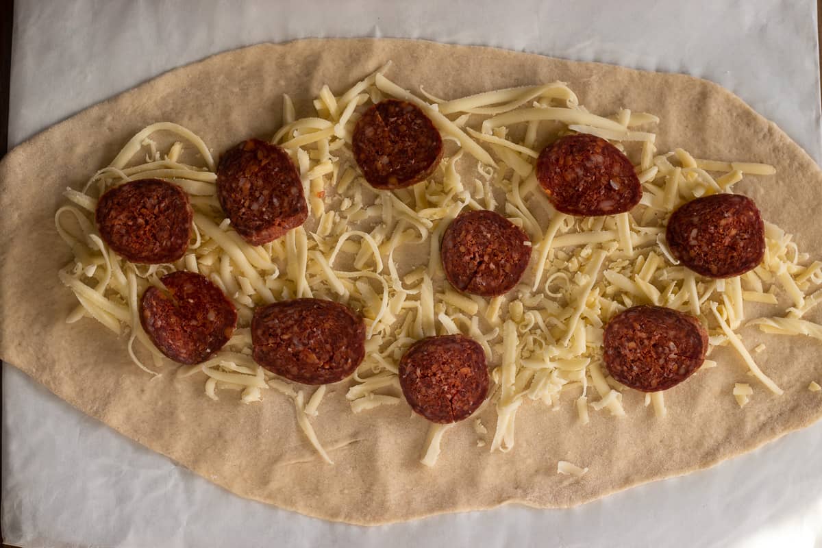 the sucuk and Kasar cheese are spread over the dough