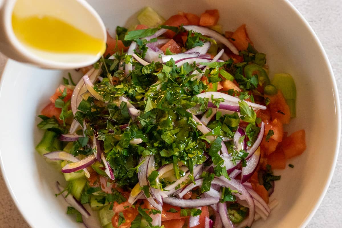 Drizzling olive oil on Coban Salatasi (Turkish Shepherd's Salad)