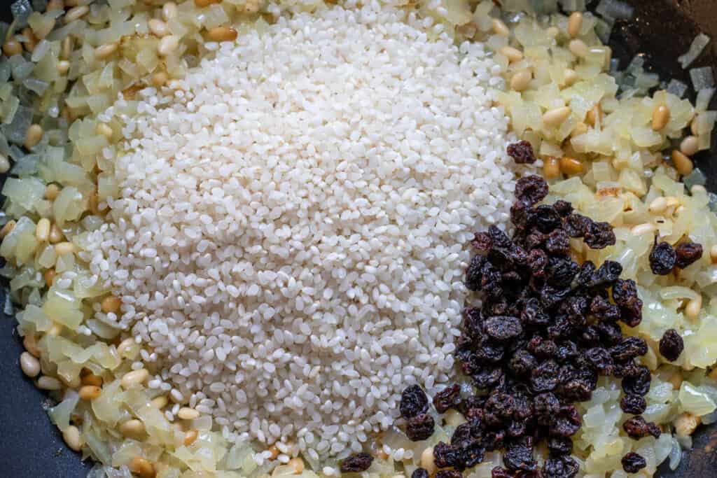 The rice and currants are added to the pan.