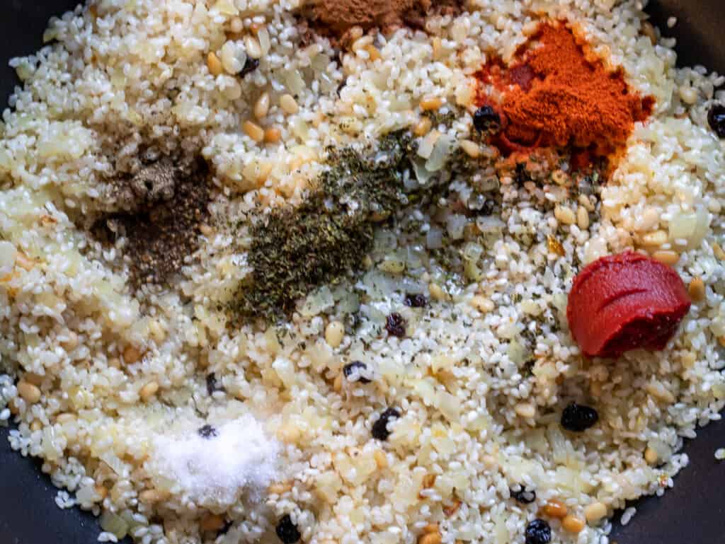 Tomato paste, spices, and fresh herbs are added to the rice.