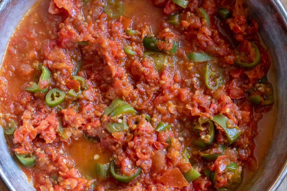 Tomatoes are cooked with peppers until soft