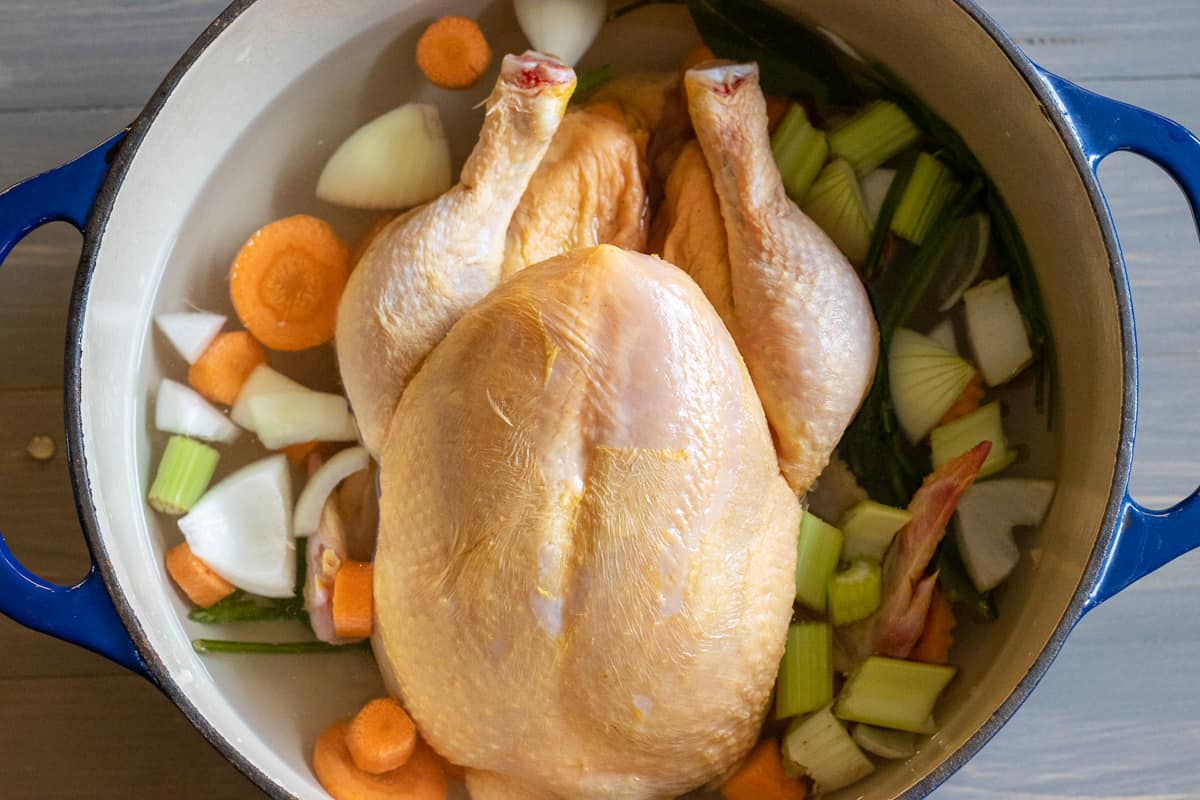 the chicken is placed in a pot with water and vegetables