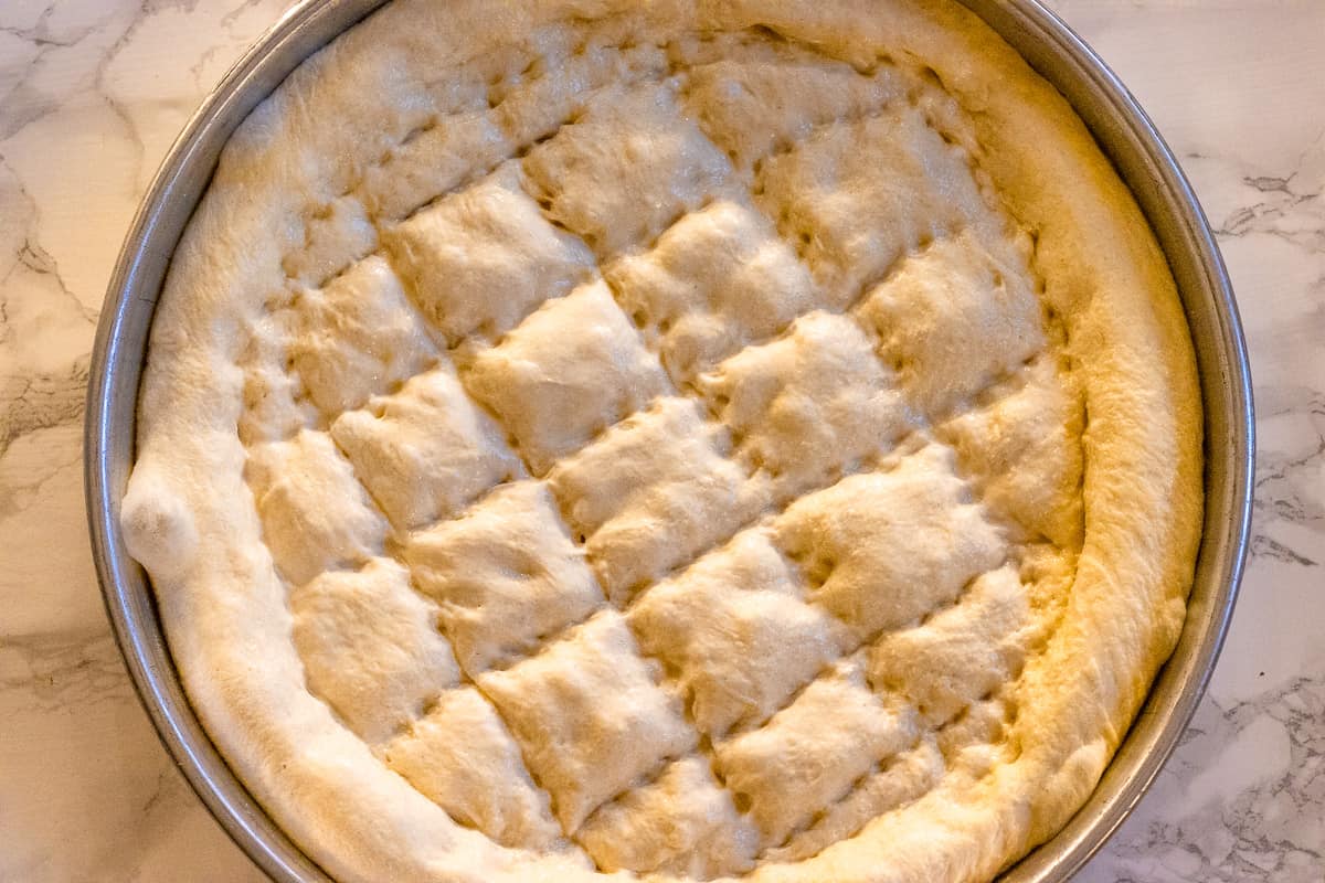 Pide is shaped on a baking tray with wet fingertips