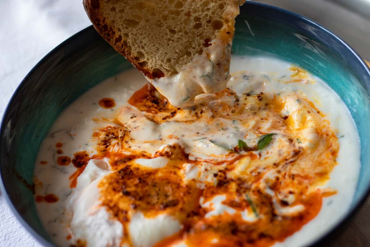 dipping a piece of bread to cilbir egg