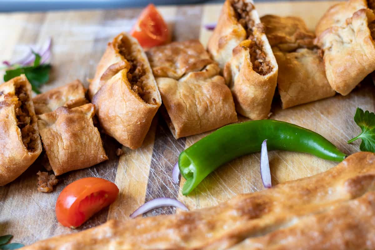 Sliced Karadeniz Pidesi served with peppers, red onions and tomatoes.