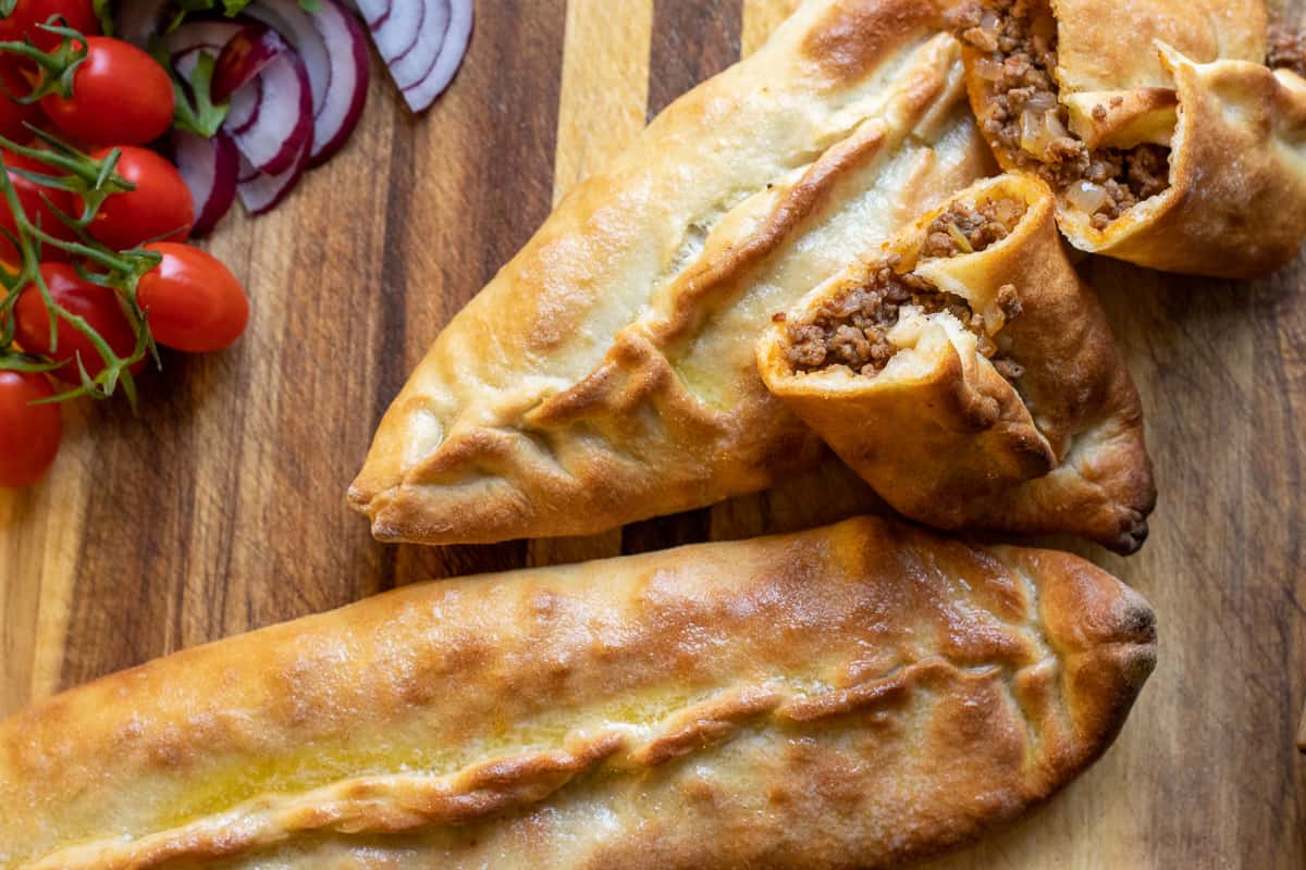 karadeniz pidesi cut in portions and served with onions, parsley and salad