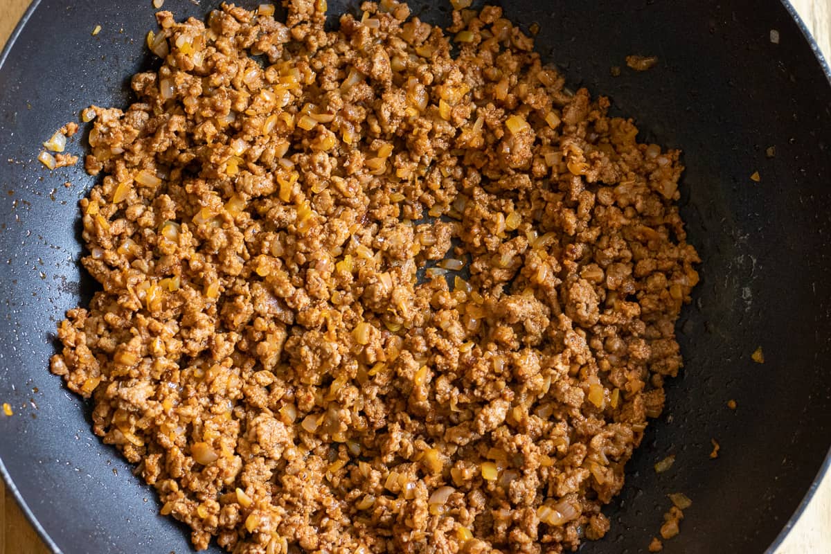 Tomato paste and spices are added to the mince and onions