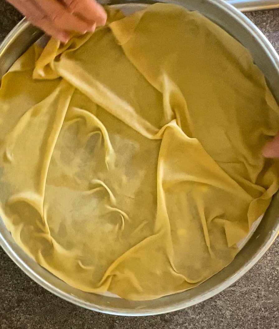 layer an uncooked yufka to the bottom of the tray