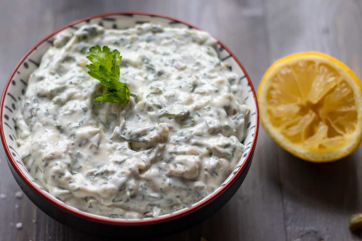tartar sauce served in a bowl with fresh parsley leaves