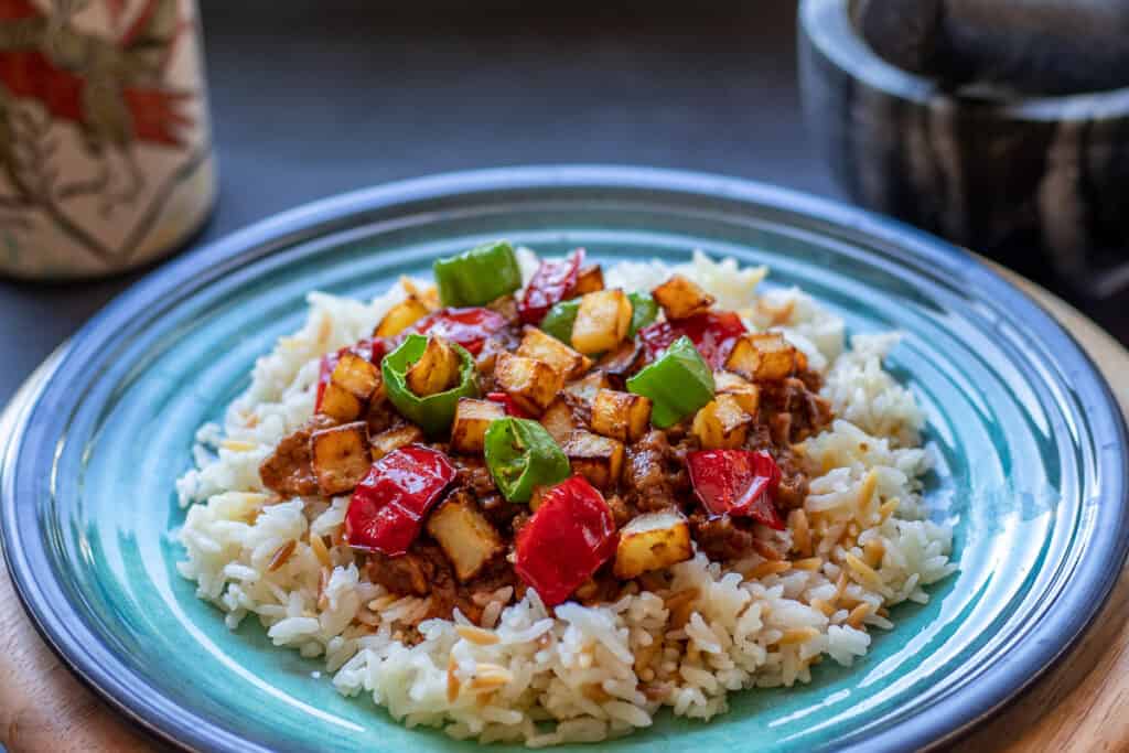 tas kebabi topped with potatoes and served on a bed of pilaf