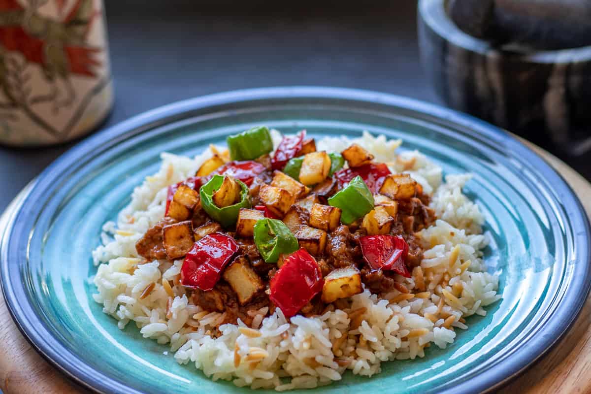tas kebabi topped with potatoes and served on a bed of pilaf