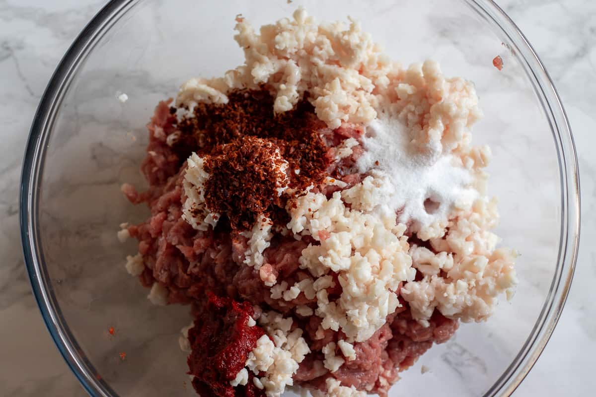 chilli, salt and pepper paste added to lamb meat in a glass bowl
