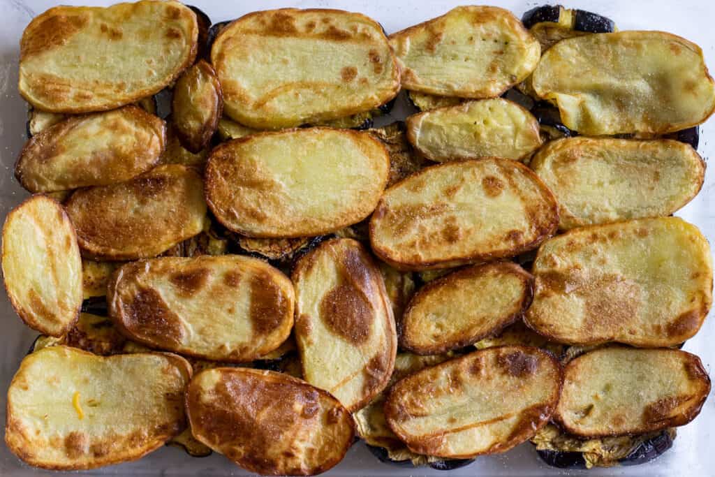 Fried potatoes are layered on top of the eggplants.