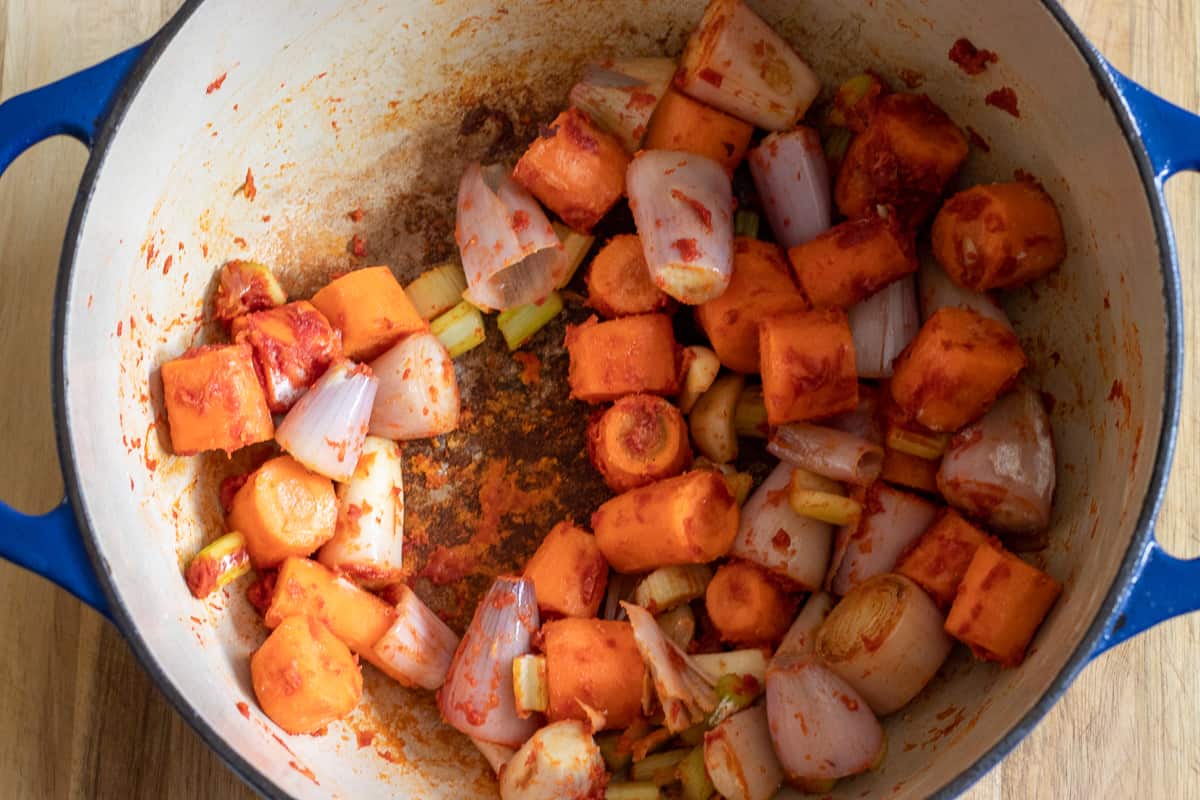The flour and tomato paste is stirred in the dutch oven