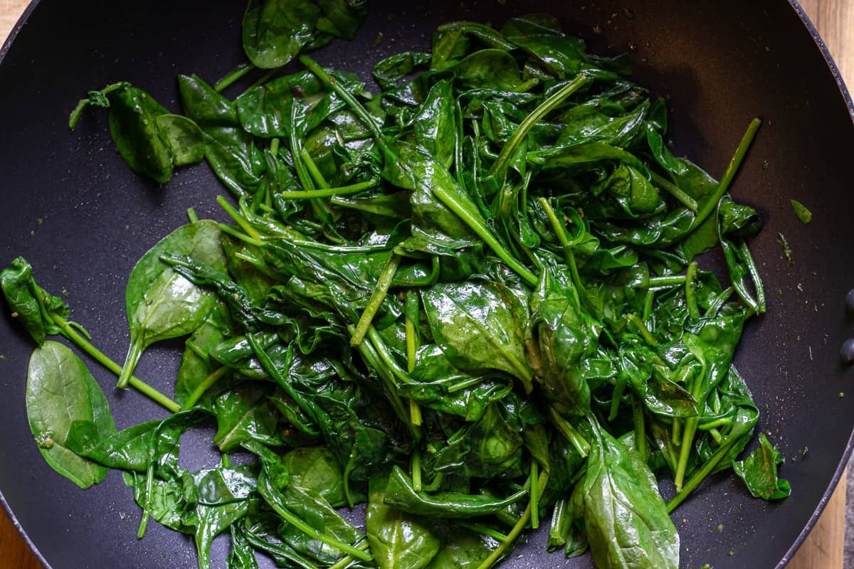 the spinach is wilted in a large wok