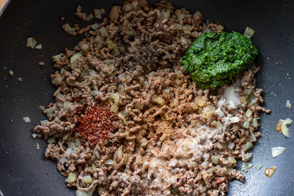 the seasoning and pesto are added to sautéed mince and onions
